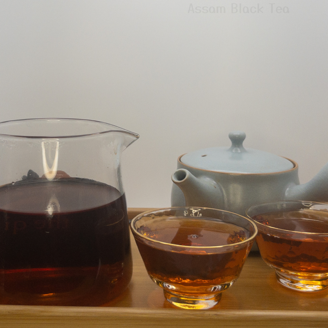 Assam Black Tea displayed after it's been brewed & steeped. Displayed alongside a serving pitcher, two tea cups & Kyusu Teapot.