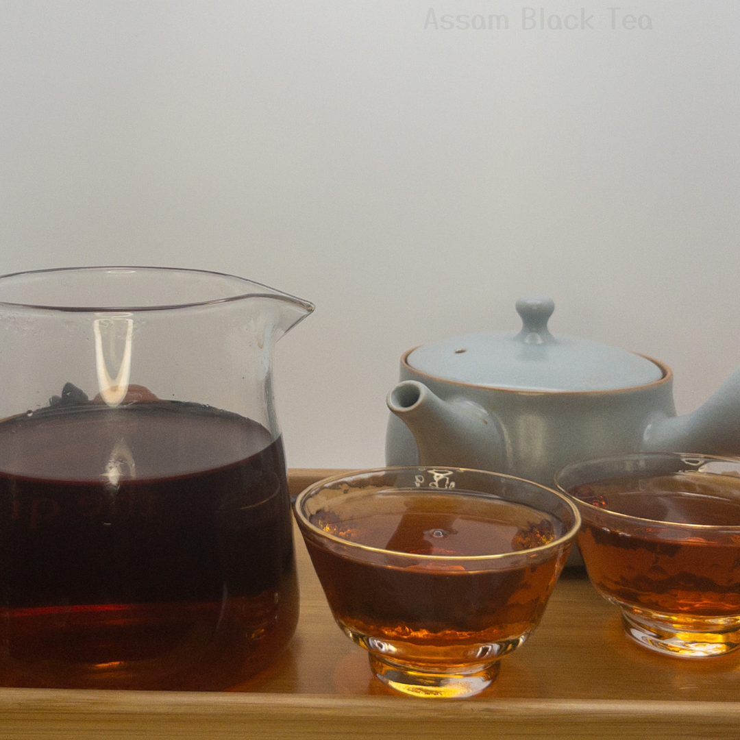 Assam Black Tea displayed after it's been brewed & steeped. Displayed alongside a serving pitcher, two tea cups & Kyusu Teapot. 