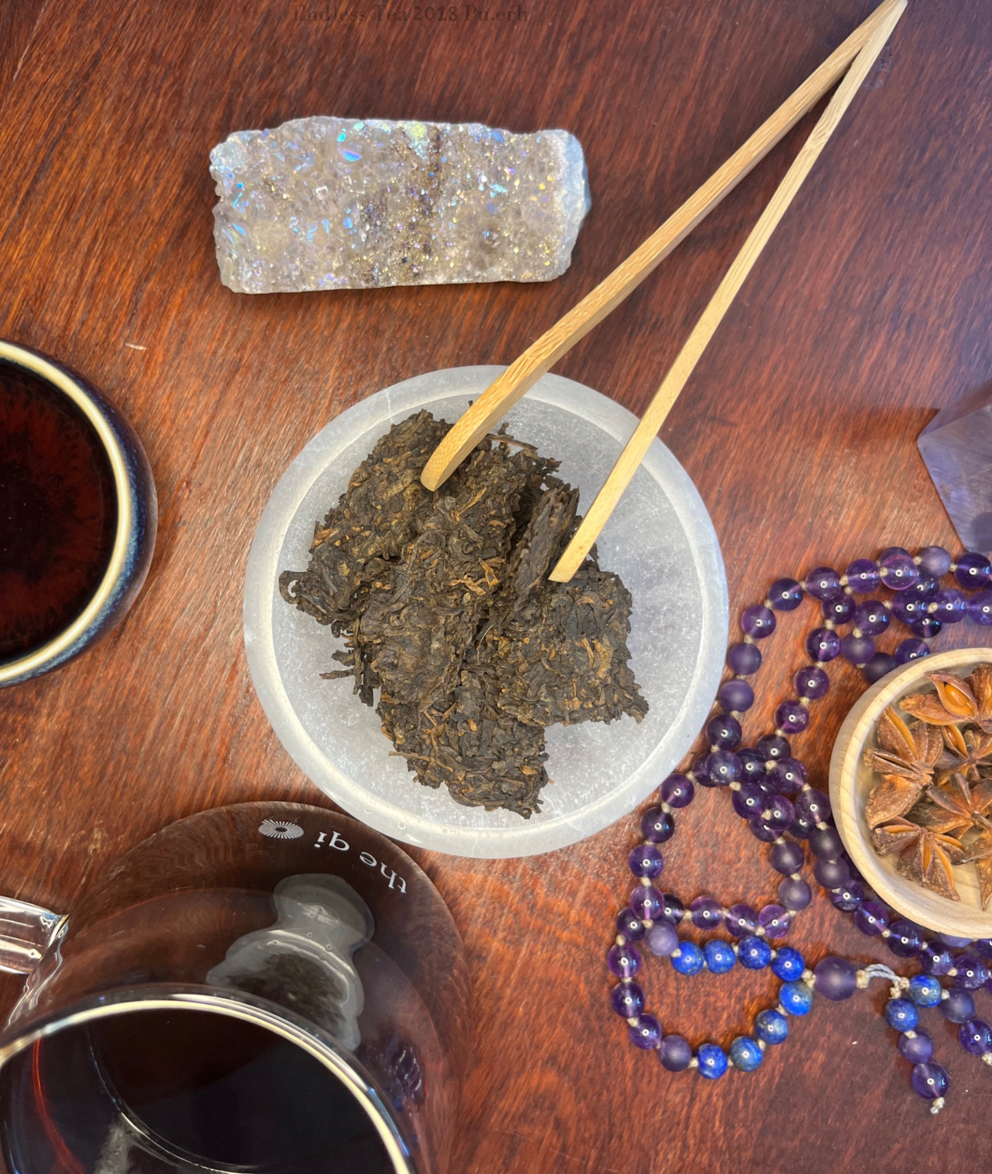 Endless Tea, Shu Pu-erh broken up & viewed from above. Tea cup with of brewed Endless Tea next to Pu erh