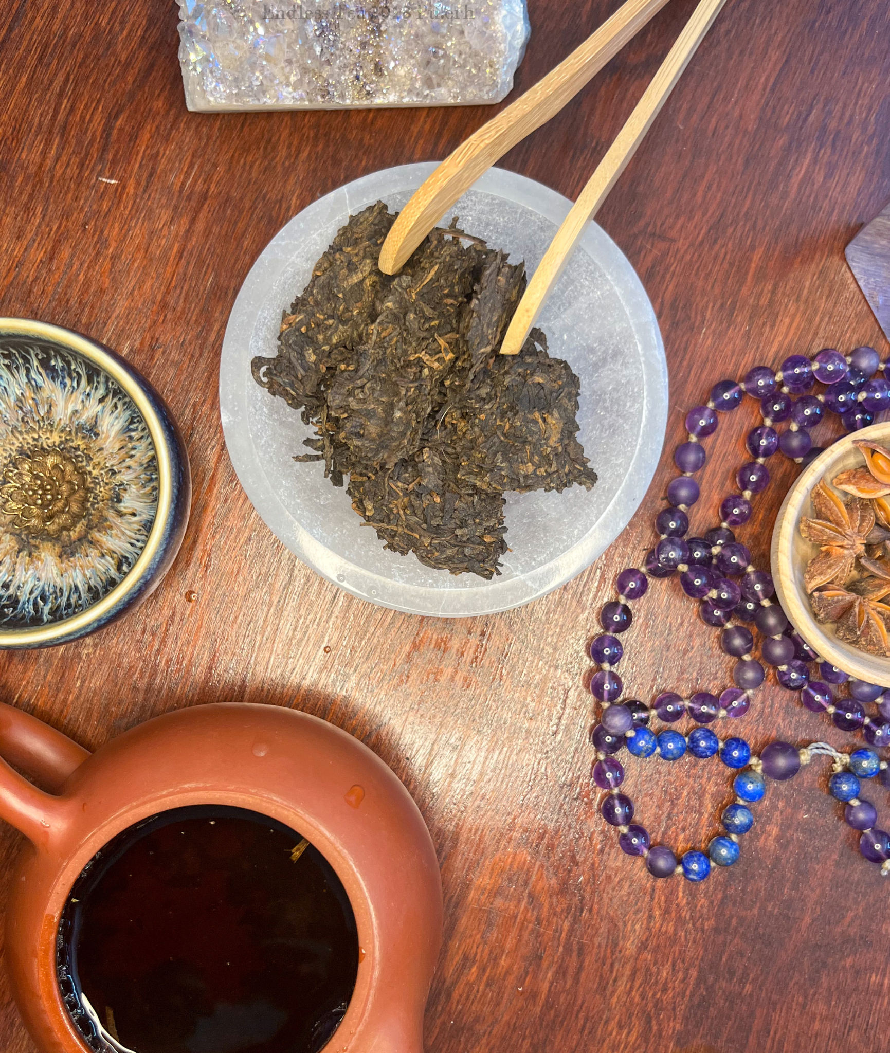 Endless Tea, Shu Pu-erh broken up & viewed from above. Pu erh steeping in a Yixing Teapot next to the Endless Tea Shu Pu-erh